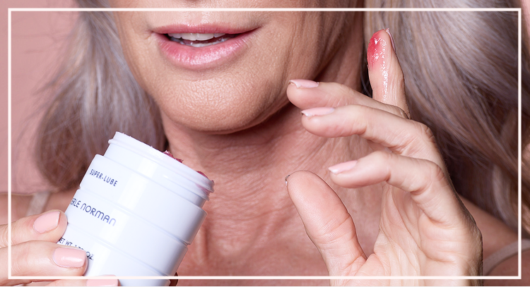 Fingers scooping cream from an open skincare jar showing product texture